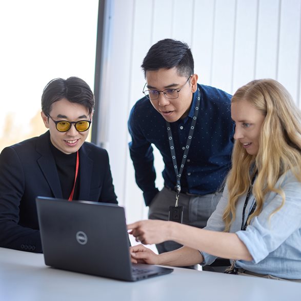 Three young colleagues working together on a laptop.